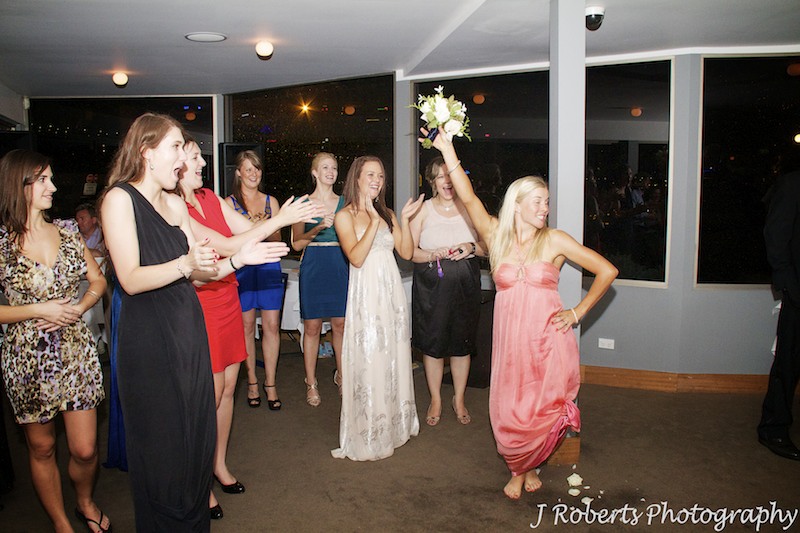 One of the girls claims the bridal bouquet at wedding reception - wedding photography sydney